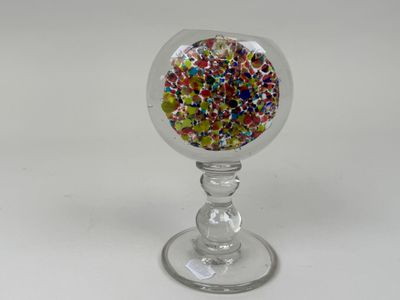 des pépites aux couleurs vives dans un verre à pied posé sur une surface blanche