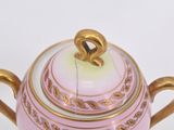 a pink and gold teapot on a white surface