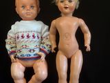 two dolls sitting next to each other on a black surface