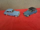 Deux petites voitures miniatures sont posées sur une surface rouge.