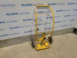 a yellow hand truck that is parked in front of a wall