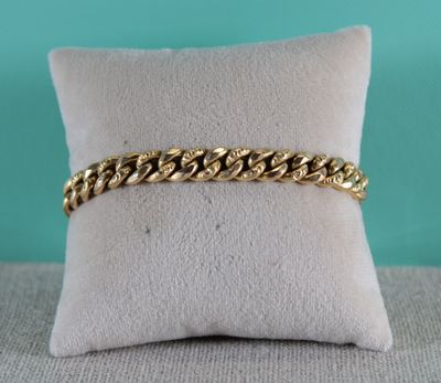 gros plan d'un bracelet en chaîne en or sur un oreiller
