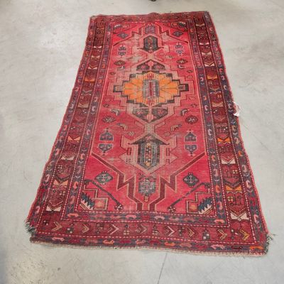 un tapis posé à même le sol dans une pièce, avec une chaise à l'arrière-plan