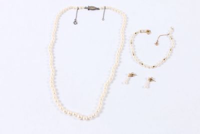 un ensemble composé d'un collier, d'un bracelet et de boucles d'oreilles, posé sur une surface blanche