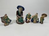 quatre figurines représentant des personnages asiatiques assis sur une surface blanche
