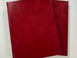 two red notebooks sitting on top of each other on a white surface