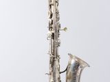 an old silver saxophone sitting on top of a white surface