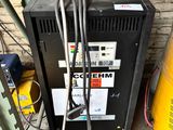 une machine posée par terre à côté d'un fût jaune