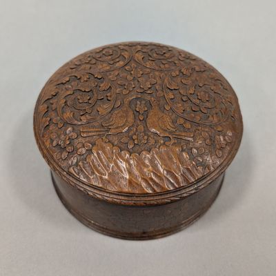 une photo d'une boîte en bois ornée de sculptures, posée sur une table