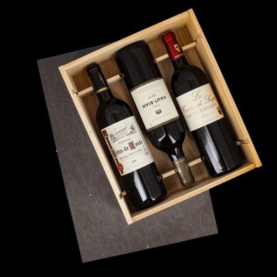 three bottles of wine in a wooden box on a table