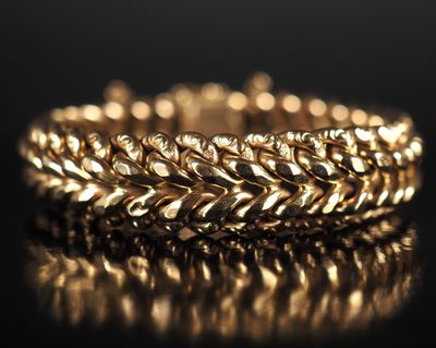 un gros plan d'un bracelet en or posé sur une surface noire