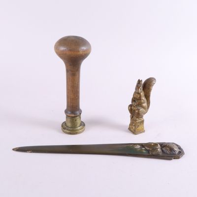 deux morceaux de métal et un manche en bois posés sur une surface blanche