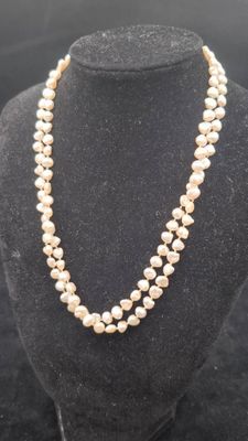 un collier de perles blanches sur un mannequin avec un fermoir en or