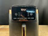a close up of a black and gold air fryer on a wooden table