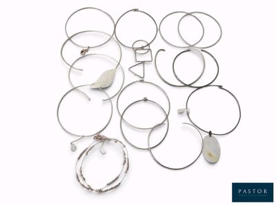 de nombreuses bagues et bracelets en argent posés sur une surface blanche