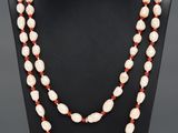 un collier de perles blanches et rouges sur un mannequin noir