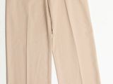 un gros plan d'un pantalon beige posé sur une surface blanche