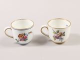 two coffee cups with floral designs on them sitting side by side