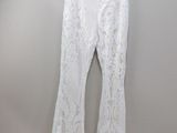 the white pants are hanging on a hanger against the wall