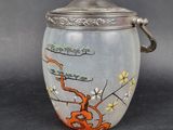 an image of a glass jar with a silver lid and a painting on it