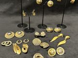 a group of gold earrings and brooches on stands