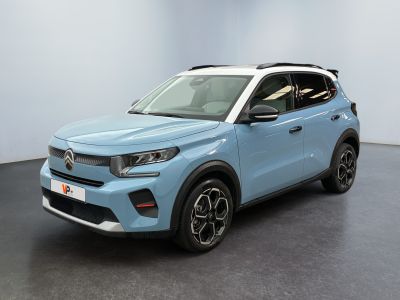 Un SUV bleu est garé dans une pièce au sol noir.