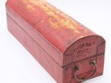 an old red suitcase with a handle on a white surface