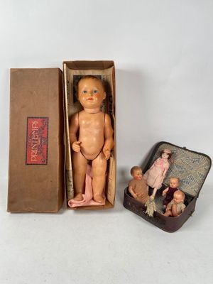 a small doll in a box next to a small doll in a suitcase