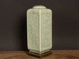 a green vase sitting on top of a wooden table