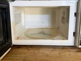 a dirty microwave sitting on top of a wooden counter