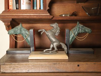 une statue représentant un cheval et une tête de cheval posée sur une bibliothèque