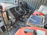 un tracteur qui prend la poussière dans un garage encombré de bric-à-brac
