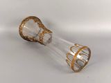 a glass vase with gold decoration on it on a white surface