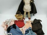 a doll that is standing next to a pile of clothes