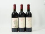 trois bouteilles de vin rouge sont alignées sur une surface blanche