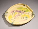 a yellow plate with a painting on it on a table