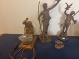 three bronze statues of a man and a woman on a blue table