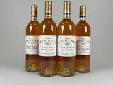 quatre bouteilles de vin sont alignées sur une surface blanche