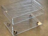 une boîte transparente munie de roulettes, posée au sol