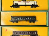trois petits trains sont rangés dans des boîtes posées sur une surface jaune
