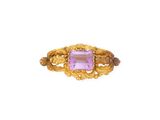gros plan d'une bague en or avec une pierre rose