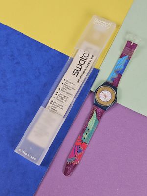 a watch sitting on a colorful surface next to a package