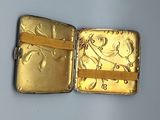 a small gold case with a gold ribbon around it