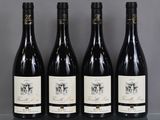 quatre bouteilles de vin sont alignées sur une table en verre