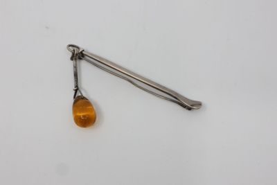 an orange glass bead hangs from a metal hook on a white surface