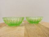 two green glass bowls sitting on top of a wooden table