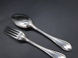 two silver spoons and a fork on a black surface