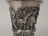 un vase en argent orné d'un motif, posé sur une table