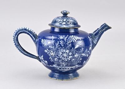 une théière bleue et blanche avec un couvercle, posée sur une table blanche