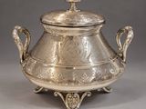 an antique silverplated teapot with a lid on a stand